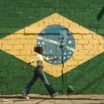 girl walking on street with brazilian flag on wall