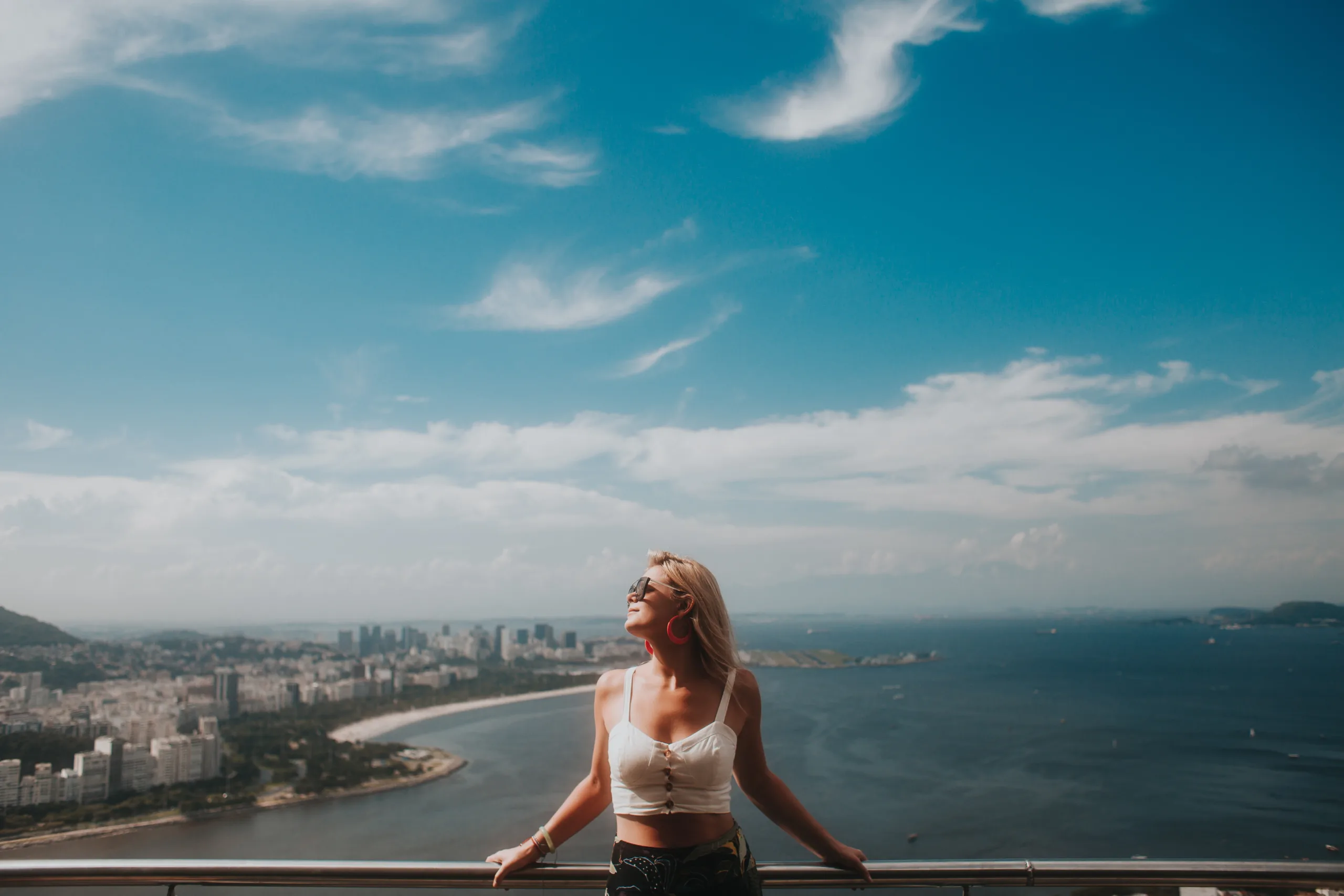 woman in white bikini standing on the edge of a building looking at the sea during